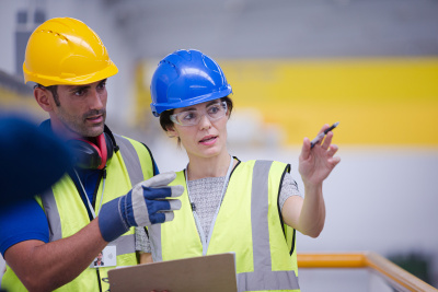 In einem industriellen Umfeld beraten sich ein Mann und eine Frau zum Thema Energieeffizienz.