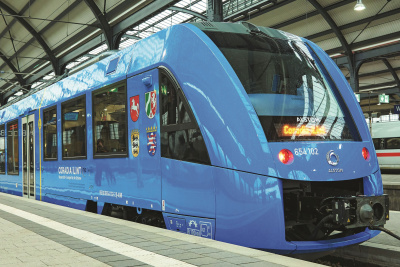 Blauer Zug mit Wasserstoffantrieb steht in einem überdachten Bahnhof.